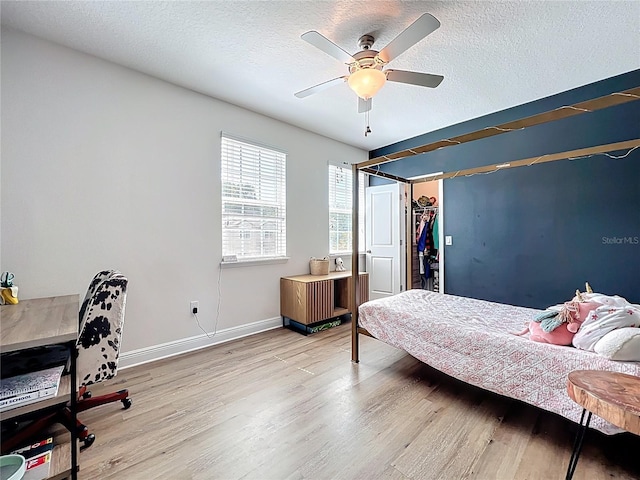 3184 Pinenut Dr, Apopka, FL 32712 - bedroom with wood finished floors, a textured ceiling, baseboards, a ceiling fan, and a walk in closet