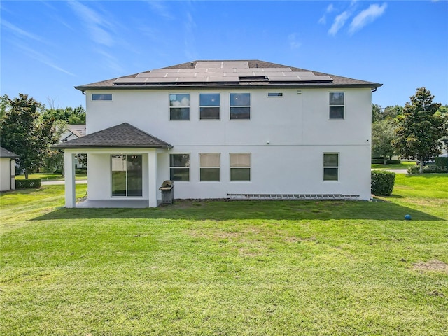 3184 Pinenut Dr, Apopka, FL 32712 - back of property featuring solar panels, a yard, stucco siding, and roof with shingles