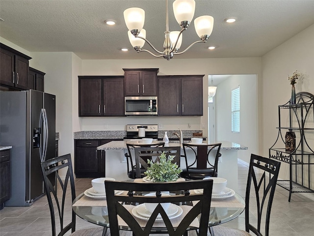 3371 Yellowtop Loop, Clermont, FL 34714 - kitchen featuring stainless steel appliances, a chandelier, dark brown cabinets, a kitchen island with sink, and a textured ceiling