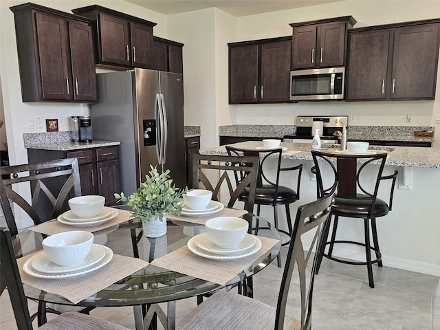 3371 Yellowtop Loop, Clermont, FL 34714 - kitchen with stainless steel appliances, dark brown cabinets, a kitchen bar, and light stone countertops
