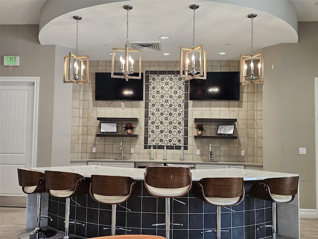3371 Yellowtop Loop, Clermont, FL 34714 - bar featuring baseboards, decorative backsplash, a chandelier, a sink, and light wood-style flooring