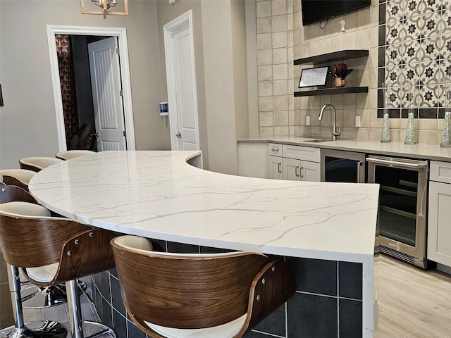 3371 Yellowtop Loop, Clermont, FL 34714 - kitchen featuring beverage cooler, a sink, white cabinetry, light stone counters, and backsplash