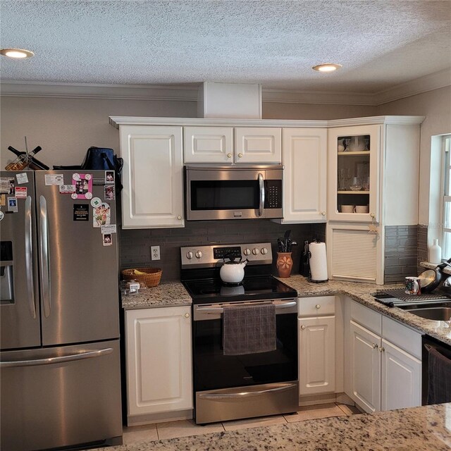 8539 Clematis Ln, Orlando, FL 32819 - kitchen featuring appliances with stainless steel finishes, ornamental molding, tasteful backsplash, white cabinetry, and a textured ceiling