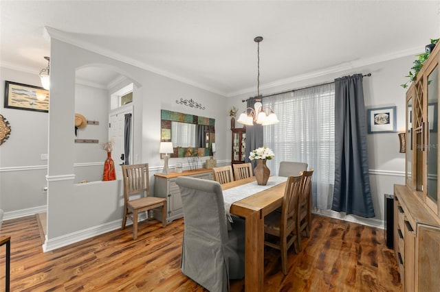 7003 Cupseed Ln, Harmony, FL 34773 - dining room featuring ornamental molding, arched walkways, wood finished floors, a chandelier, and baseboards