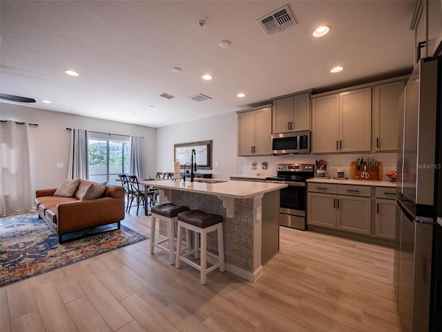 391 Cape Honeysuckle Pl, Sanford, FL 32771 - kitchen featuring stainless steel appliances, a sink, light wood-style floors, a kitchen breakfast bar, and light countertops