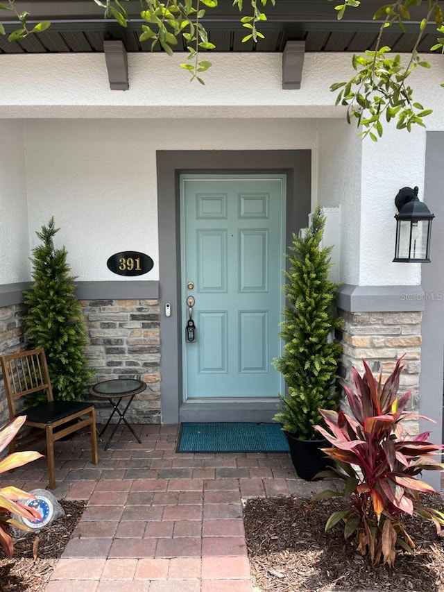 391 Cape Honeysuckle Pl, Sanford, FL 32771 - entrance to property with stone siding, stucco siding, and covered porch