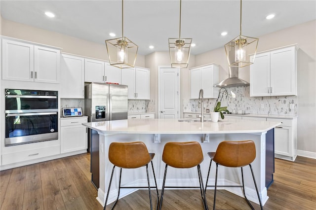 16013 Silver Brook Way, Winter Garden, FL 34787 - kitchen with stainless steel appliances, white cabinetry, wall chimney exhaust hood, an island with sink, and light countertops
