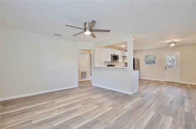 222 E Atwater Ave, Eustis, FL 32726 - unfurnished living room featuring light wood-style flooring, a ceiling fan, a textured ceiling, and baseboards