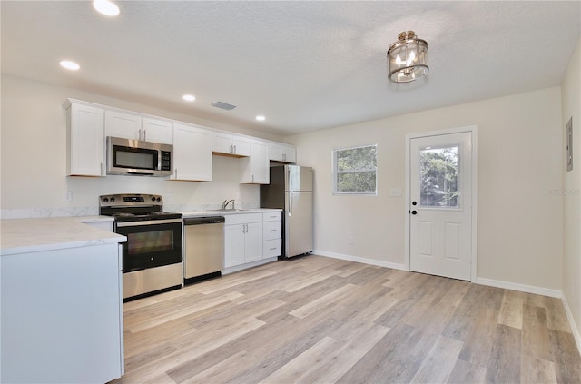 222 E Atwater Ave, Eustis, FL 32726 - kitchen featuring appliances with stainless steel finishes, white cabinets, light wood-style flooring, recessed lighting, and baseboards