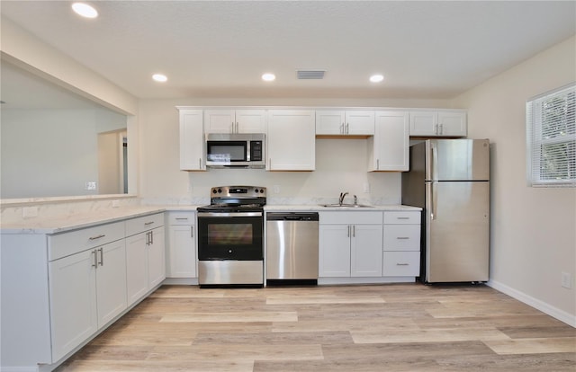 222 E Atwater Ave, Eustis, FL 32726 - kitchen with stainless steel appliances, white cabinets, a sink, recessed lighting, and light wood-style floors