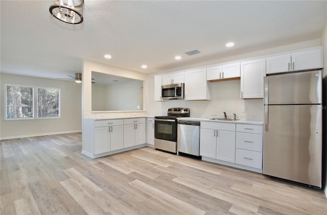222 E Atwater Ave, Eustis, FL 32726 - kitchen with stainless steel appliances, light countertops, light wood-style floors, white cabinetry, and a sink