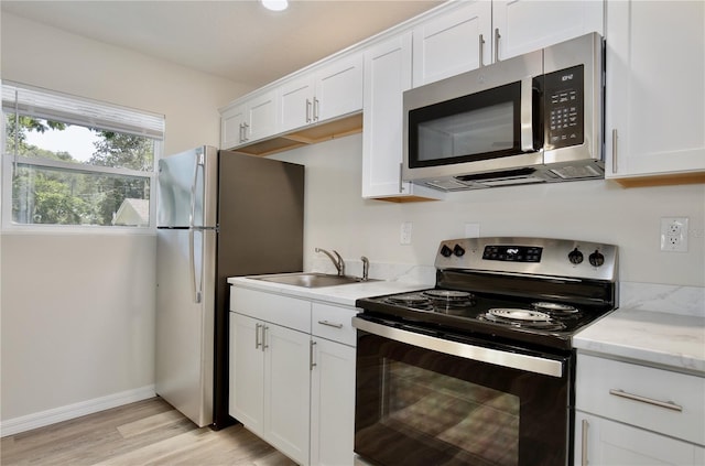 222 E Atwater Ave, Eustis, FL 32726 - kitchen featuring appliances with stainless steel finishes, a sink, white cabinetry, light wood finished floors, and light stone counters