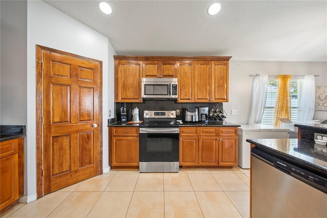 2332 Andrews Valley Dr, Kissimmee, FL 34758 - kitchen with stainless steel appliances, brown cabinets, backsplash, a textured ceiling, and dark stone counters