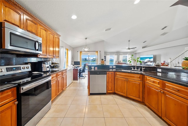 2332 Andrews Valley Dr, Kissimmee, FL 34758 - kitchen featuring stainless steel appliances, lofted ceiling, brown cabinetry, dark stone countertops, and light tile patterned flooring