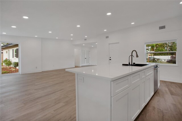 4201 Mizell St, Orlando, FL 32812 - kitchen with a sink, light wood finished floors, white cabinets, light countertops, and a kitchen island with sink