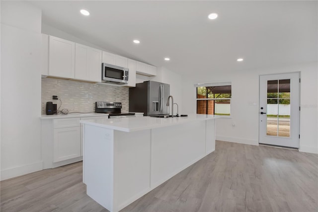 4201 Mizell St, Orlando, FL 32812 - kitchen featuring appliances with stainless steel finishes, light wood finished floors, decorative backsplash, white cabinets, and light countertops