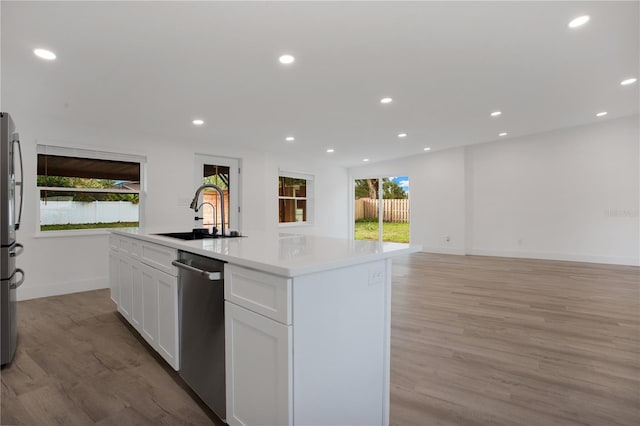 4201 Mizell St, Orlando, FL 32812 - kitchen with appliances with stainless steel finishes, a sink, white cabinets, light wood finished floors, and recessed lighting