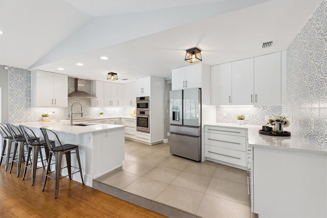1327 Bridgeport Dr, Winter Park, FL 32789 - kitchen with stainless steel appliances, wall chimney range hood, a peninsula, backsplash, and lofted ceiling