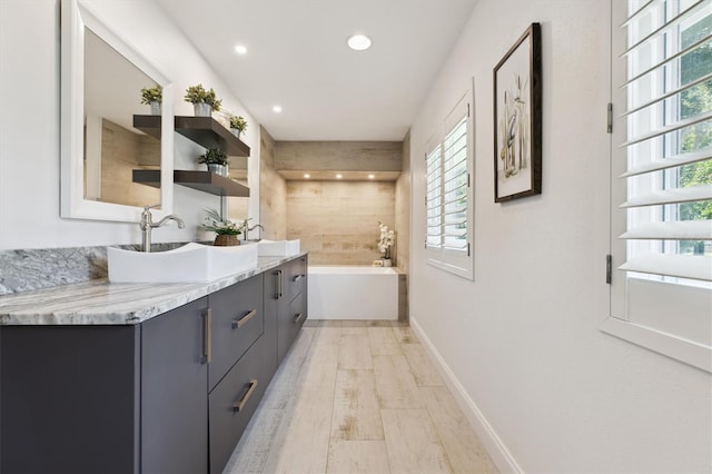 1327 Bridgeport Dr, Winter Park, FL 32789 - bathroom with double vanity, a bath, plenty of natural light, wood finished floors, and recessed lighting