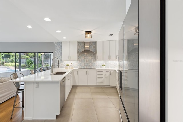 1327 Bridgeport Dr, Winter Park, FL 32789 - kitchen with wall chimney exhaust hood, a peninsula, a kitchen bar, decorative backsplash, and white cabinets