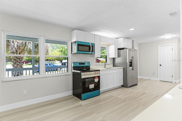174 Pine Grove Ct, Daytona Beach, FL 32119 - kitchen featuring stainless steel appliances, a sink, light wood-type flooring, a textured ceiling, and healthy amount of natural light