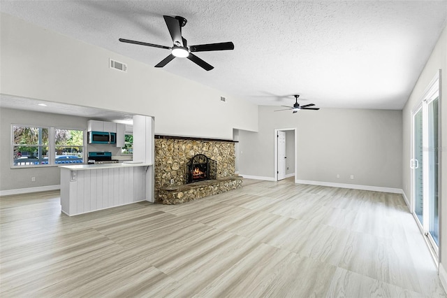 174 Pine Grove Ct, Daytona Beach, FL 32119 - unfurnished living room with a ceiling fan, a textured ceiling, light wood finished floors, a stone fireplace, and baseboards