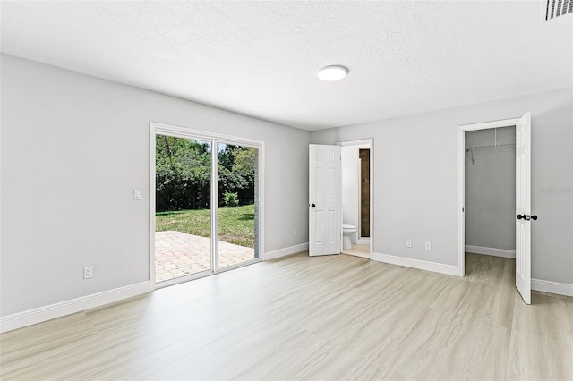 174 Pine Grove Ct, Daytona Beach, FL 32119 - unfurnished bedroom featuring access to outside, light wood finished floors, baseboards, a walk in closet, and ensuite bath