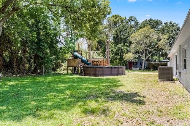 174 Pine Grove Ct, Daytona Beach, FL 32119 - view of grassy yard with central AC, an outdoor pool, and view of wooded area