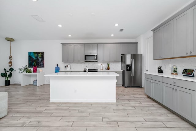 652 Benoi Dr, Davenport, FL 33896 - kitchen with stainless steel appliances, gray cabinetry, decorative backsplash, recessed lighting, and light wood-type flooring