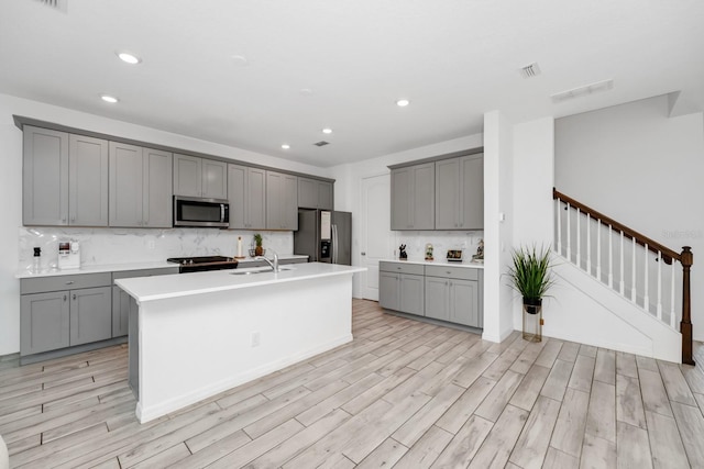 652 Benoi Dr, Davenport, FL 33896 - kitchen with gray cabinetry, stainless steel appliances, a sink, backsplash, and an island with sink