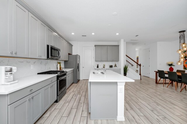 652 Benoi Dr, Davenport, FL 33896 - kitchen with stainless steel appliances, a sink, gray cabinets, light wood-style floors, and tasteful backsplash