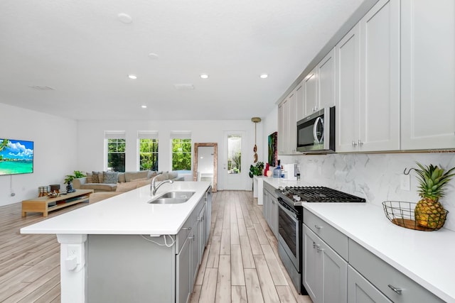 652 Benoi Dr, Davenport, FL 33896 - kitchen with stainless steel appliances, a sink, open floor plan, an island with sink, and gray cabinets