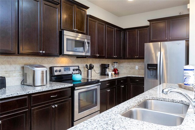 1979 Majorca Dr, Kissimmee, FL 34747 - kitchen featuring appliances with stainless steel finishes, a sink, light stone counters, and backsplash