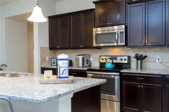 1979 Majorca Dr, Kissimmee, FL 34747 - kitchen featuring stainless steel appliances, a sink, light stone counters, decorative backsplash, and dark brown cabinetry