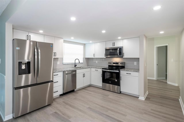 838 Haulover Dr, Altamonte Springs, FL 32714 - kitchen featuring appliances with stainless steel finishes, a sink, white cabinets, tasteful backsplash, and light wood finished floors