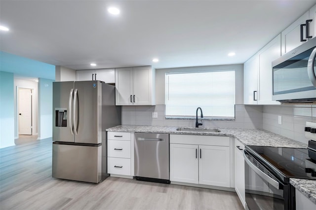 838 Haulover Dr, Altamonte Springs, FL 32714 - kitchen featuring stainless steel appliances, a sink, light wood-style floors, light stone counters, and white cabinetry