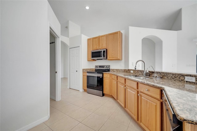 10955 Lemay Dr, Clermont, FL 34711 - kitchen with appliances with stainless steel finishes, light tile patterned flooring, arched walkways, light stone counters, and light brown cabinetry