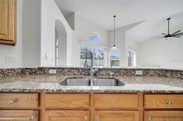 10955 Lemay Dr, Clermont, FL 34711 - kitchen with light stone countertops, a ceiling fan, vaulted ceiling, pendant lighting, and arched walkways