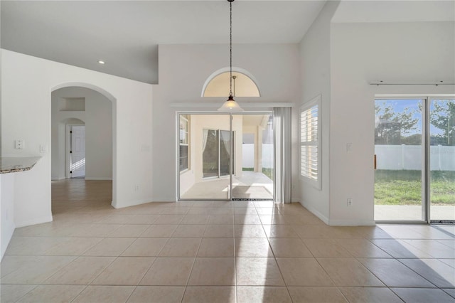 10955 Lemay Dr, Clermont, FL 34711 - unfurnished dining area featuring light tile patterned flooring, arched walkways, a high ceiling, and recessed lighting