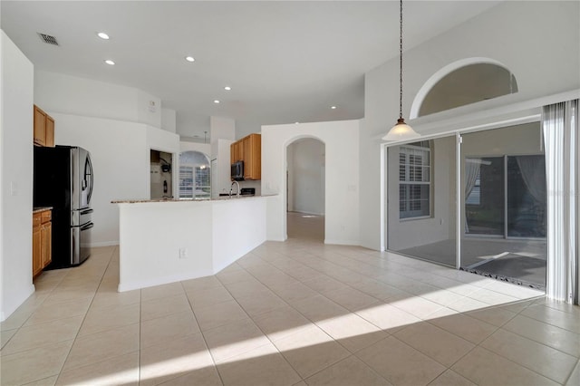 10955 Lemay Dr, Clermont, FL 34711 - kitchen featuring freestanding refrigerator, arched walkways, brown cabinetry, light tile patterned floors, and recessed lighting