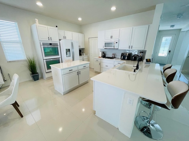 14753 Snowy Egret St, Winter Garden, FL 34787 - kitchen featuring white appliances, a sink, a kitchen bar, a peninsula, and white cabinetry