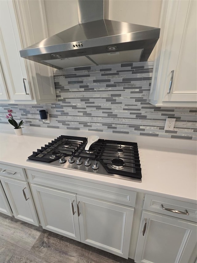 6129 Citrus Grove Ct, Saint Cloud, FL 34771 - kitchen featuring wall chimney exhaust hood, stainless steel gas stovetop, white cabinetry, decorative backsplash, and wood finished floors