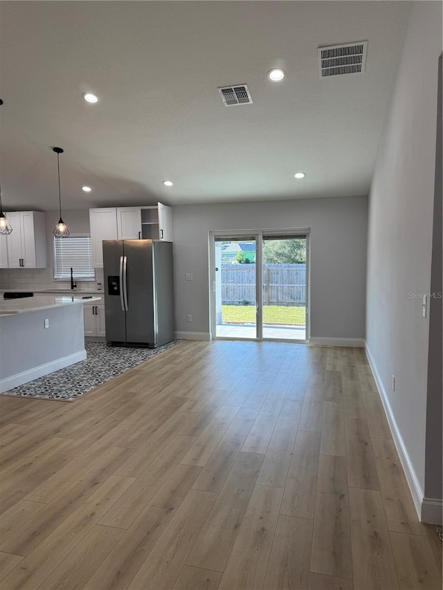 468 Marion Oaks Blvd, Ocala, FL 34473 - kitchen featuring stainless steel fridge, light countertops, white cabinets, light wood-style floors, and pendant lighting