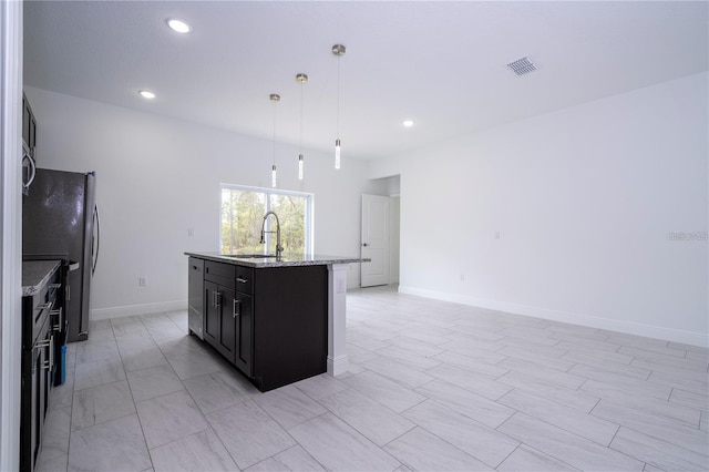 9825 N Swanee Ter, Dunnellon, FL 34433 - kitchen with a sink, an island with sink, dark cabinetry, recessed lighting, and hanging light fixtures