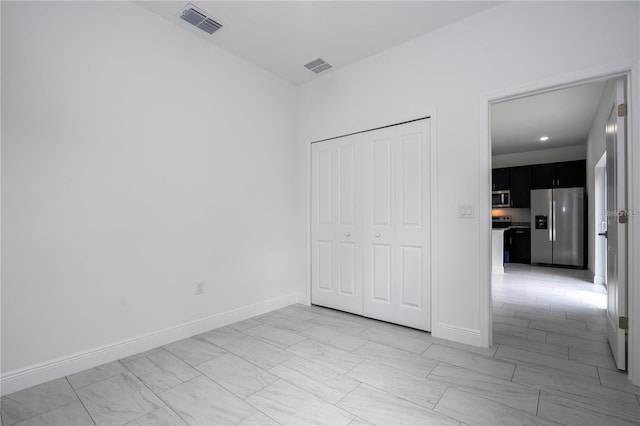 9825 N Swanee Ter, Dunnellon, FL 34433 - unfurnished bedroom featuring stainless steel refrigerator with ice dispenser, light marble finish floors, baseboards, and a closet
