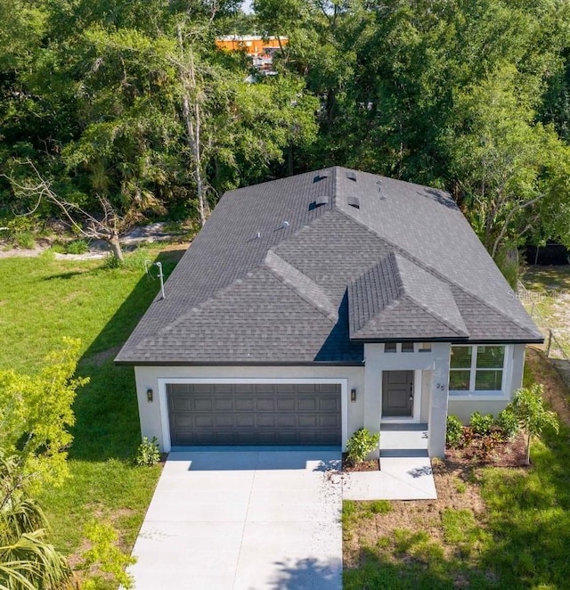 25 W 7th St, Apopka, FL 32703 - view of front of property with a shingled roof, stucco siding, a garage, a front lawn, and concrete driveway