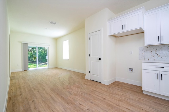 25 W 7th St, Apopka, FL 32703 - kitchen with light wood-style floors, white cabinets, backsplash, and baseboards