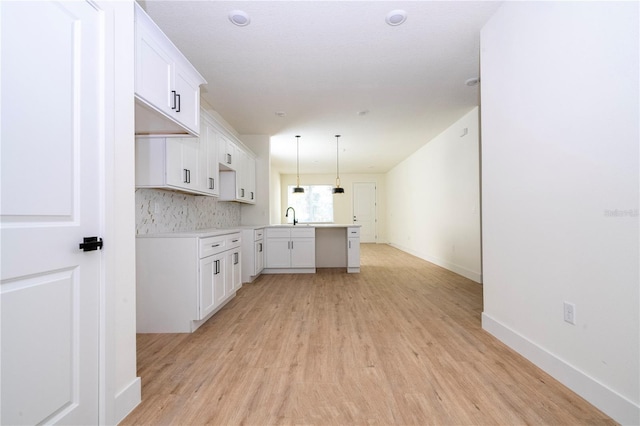 25 W 7th St, Apopka, FL 32703 - kitchen with light wood-style floors, a sink, white cabinetry, baseboards, and light countertops