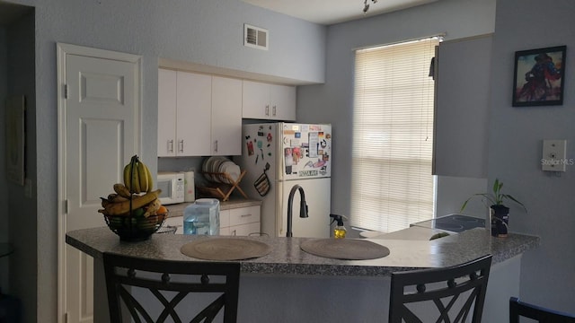6316 Raleigh St Unit 401, Orlando, FL 32835 - kitchen with white appliances, a kitchen bar, white cabinetry, and a peninsula