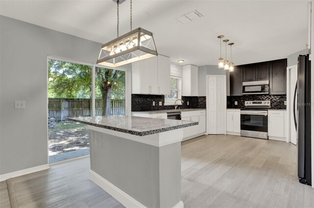 809 Deer Glen Ct, Fruitland Park, FL 34731 - kitchen featuring appliances with stainless steel finishes, backsplash, light wood-style floors, and healthy amount of natural light